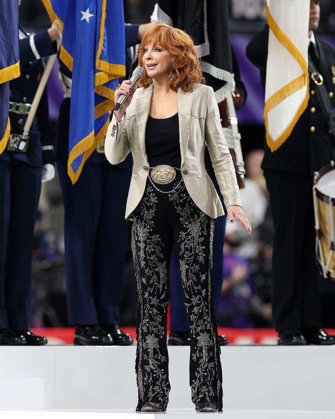 #Reba in custom #RalphLauren for the #SuperBowlLVIII national anthem performance at Allegiant Stadium in Las Vegas, NV. 

The custom look featured hand-embroidered bootcut trousers finished with suede and crystal-beaded fringe along the seams. To finish the look, the singer and actor wore a Western-inspired platinum lamé blazer that sparkled with more than 175,800 Swarovski crystals.