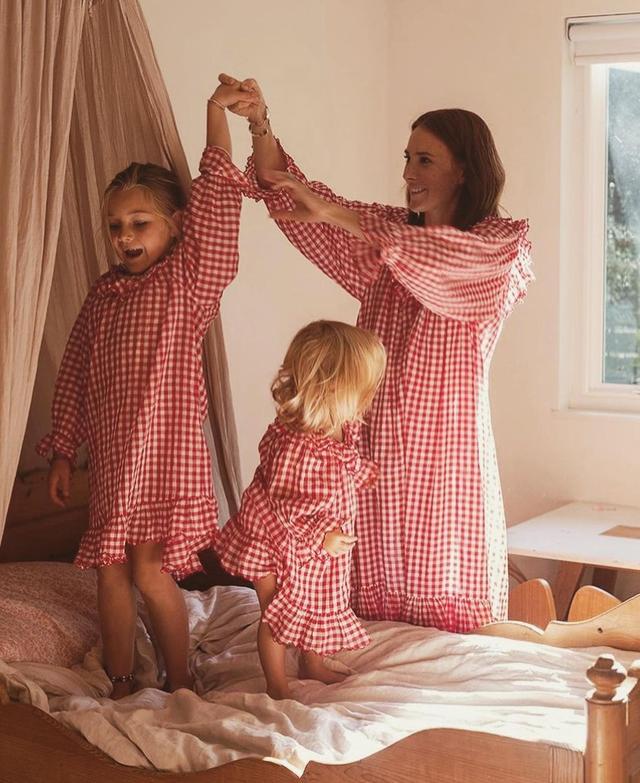 Sway with me 🍒❣️Matching holiday moments, @couldihavethat and her sweetest girls in our @heathertaylorhome Cherry Gingham cozies! 🎁

~

Image Description // A morning scene captures Samantha and two her little ones playing in the children’s bedroom as she wears a red and white, gingham nightgown, and the children wear matching red and white, gingham dresses.